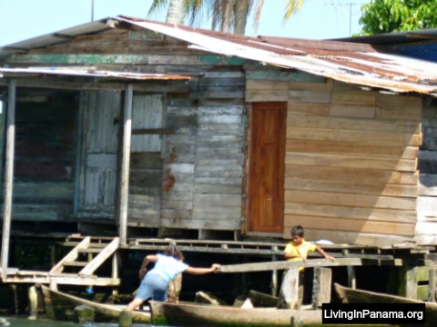 Two childern getting into canoes in front of shack