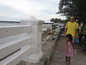 man and young girl walking and looking at cement rail being built