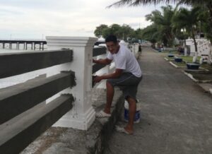 Man painting new cement railings white