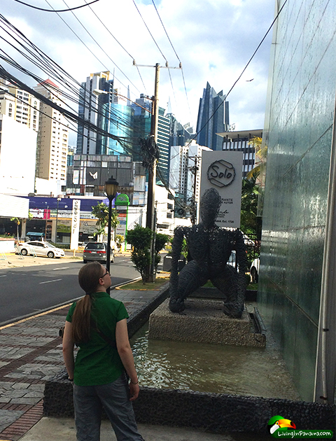 cityscape with close up of girl, wire statue, and cascading water over vertical wall