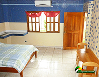 light filled hotel room with 1 bed, a table, and AC