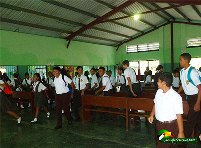 Lots of kids in school uniforms leaving the school