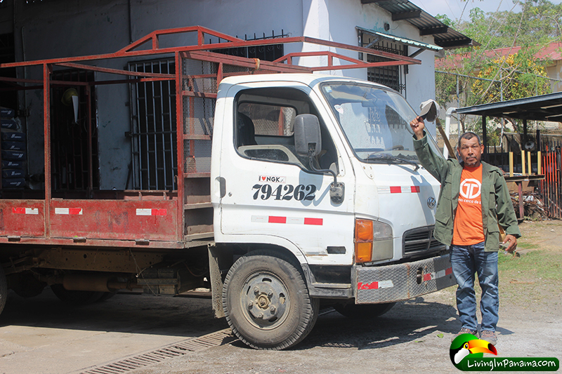 Building supply delivery truck with driver standing in front of it.