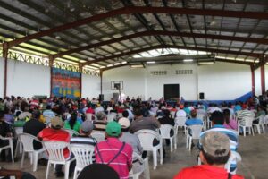 Lots of folks sitting & listening in gym