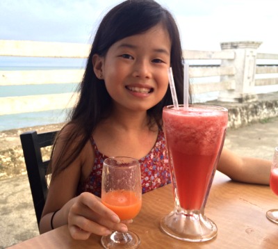 young girl at waterfront cafe drinking a smoothie