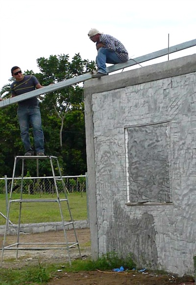 2 men using M2 panels and cement to build a house