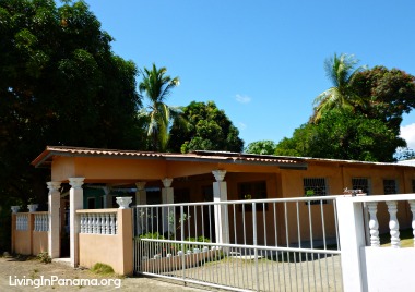 Spacious looking tan house with large white gate and fence